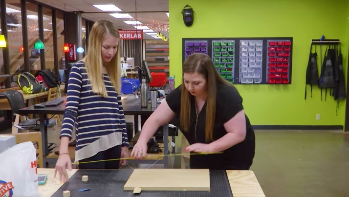 Two graduate students of education and human services measuring a wood board
