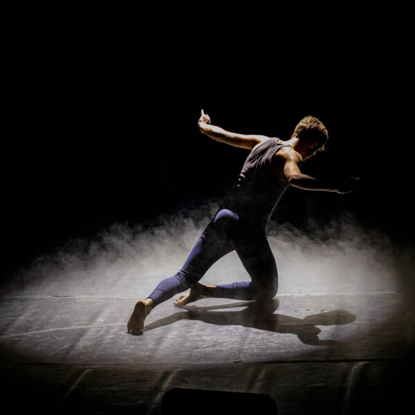 Student dancing with a black background behind