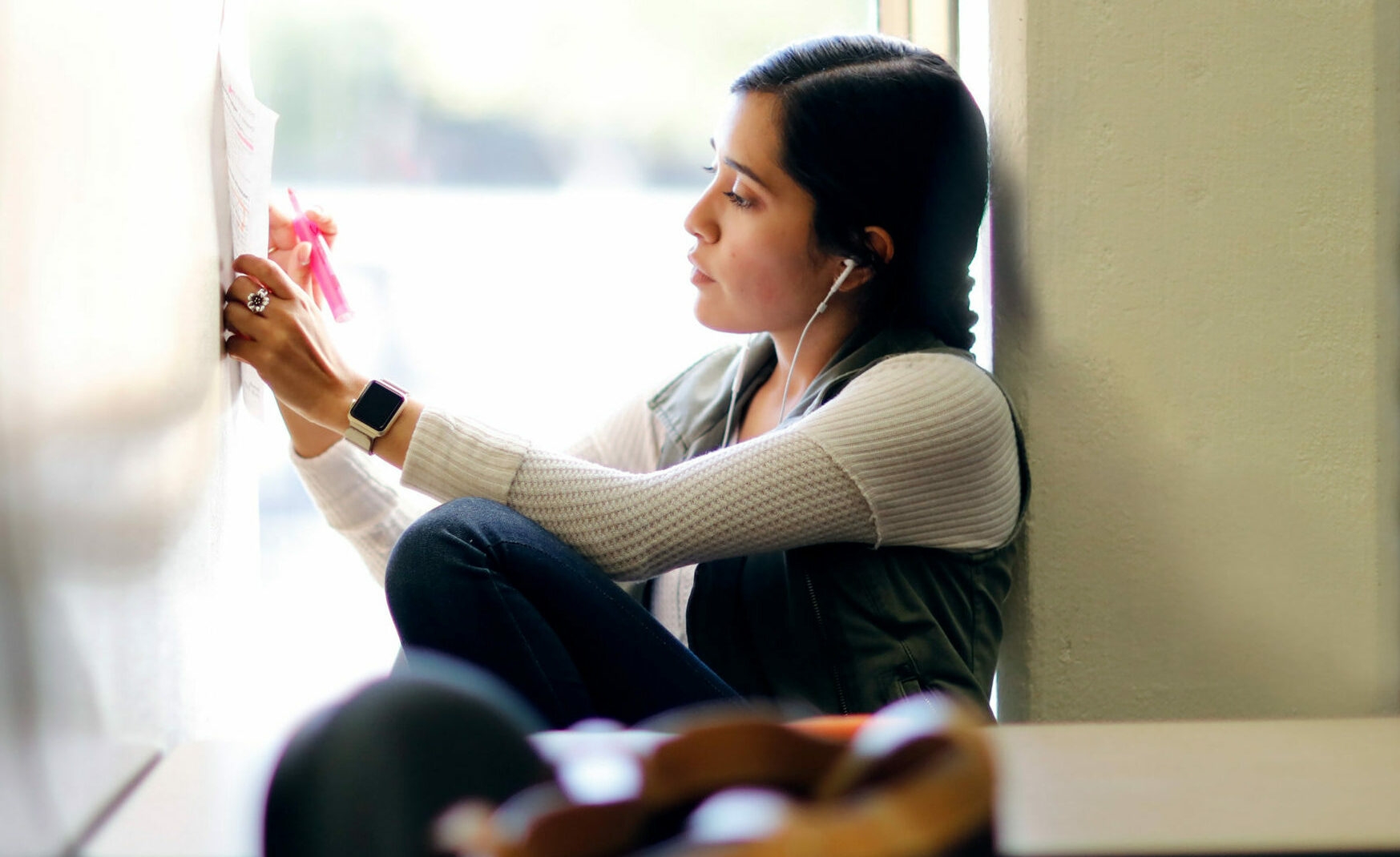 a student in the graduate certificate program wearing earphones and highlighting her study notes