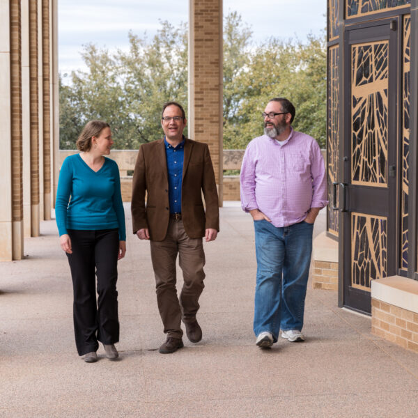 Three professors are walking outside of a building and chatting, Graduate School of Theology