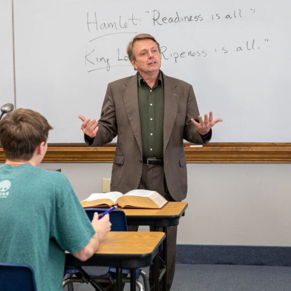 A professor standing in front of a whiteboard and teaching a literature class