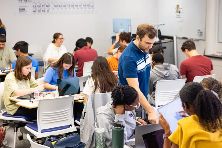 A professor walks around helping students during a chemistry class.