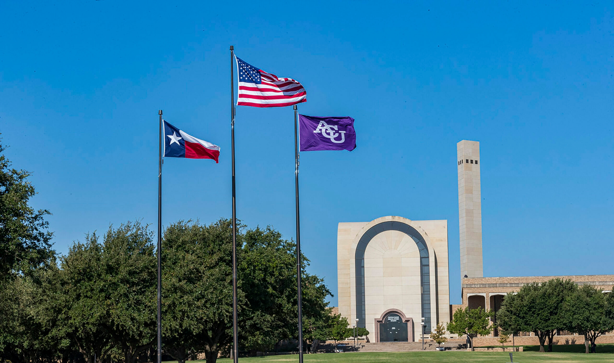 The flags of Texas, America, and ACU waving in the wind