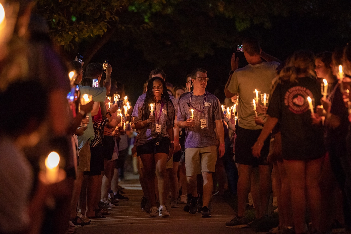 Students walking with lighted candles at the Candlelight Devo event