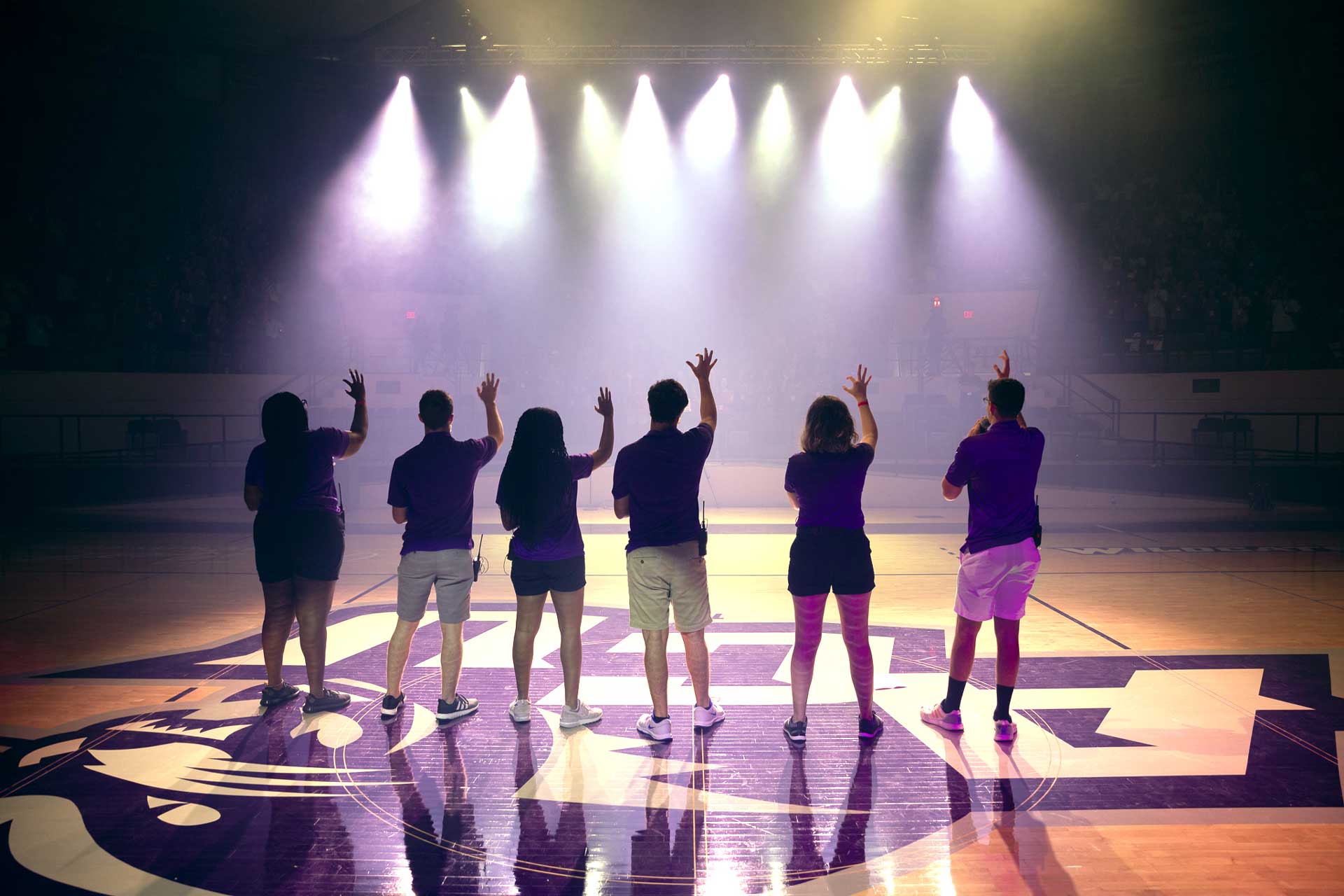 students performing in a basketball stadium