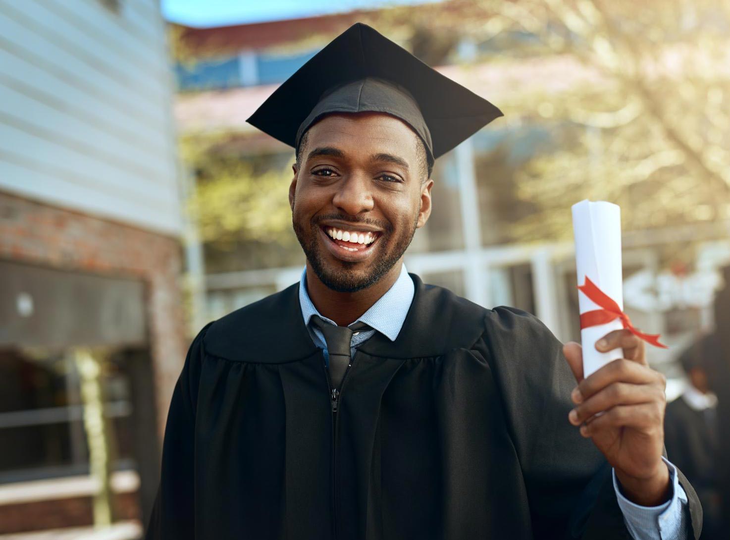 Student smiles while holding his diploma.