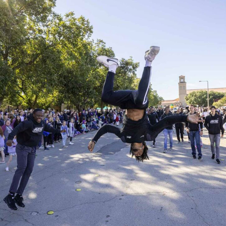 Student performs a flip in a ACU Homecoming parade