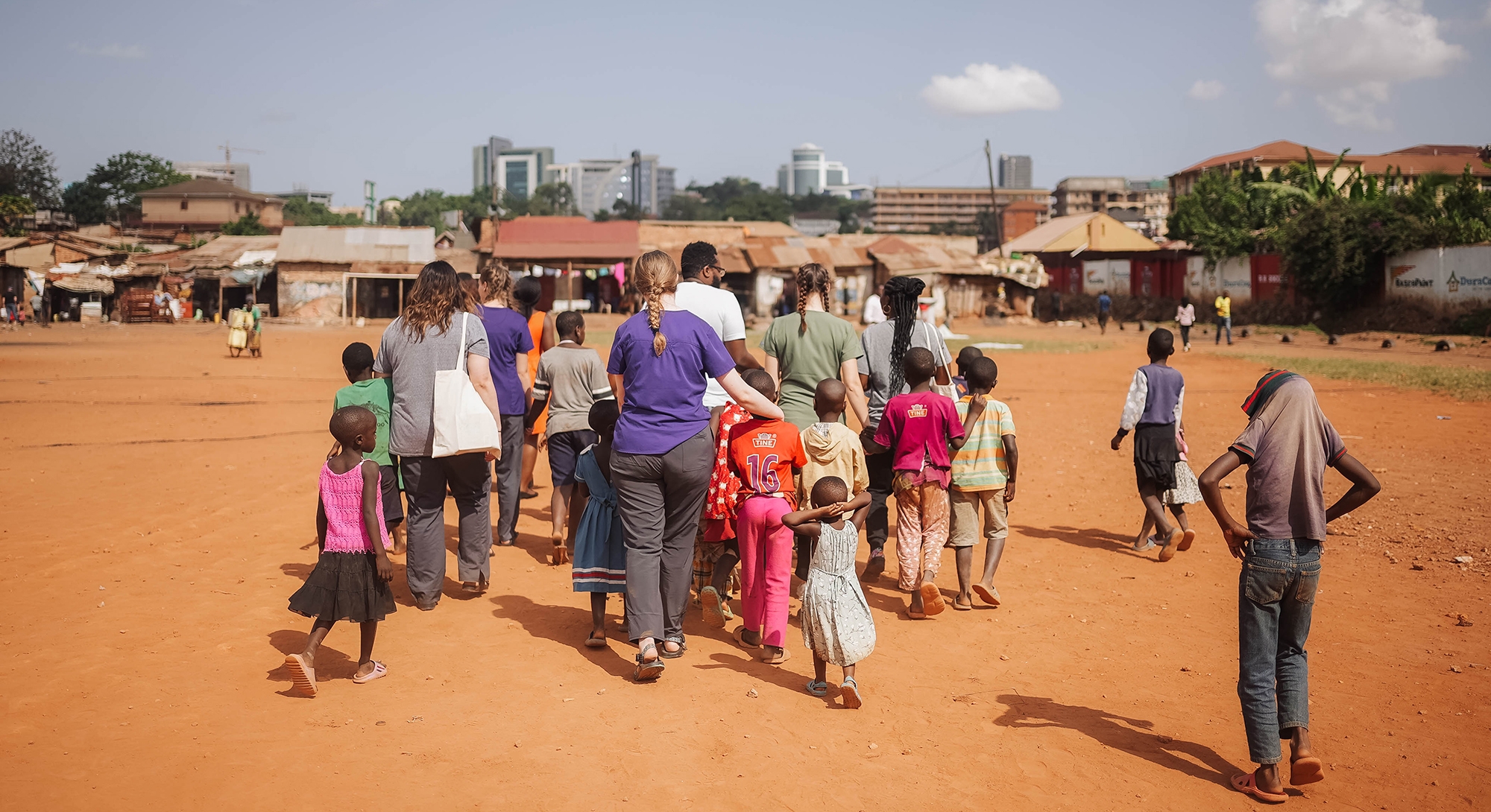 ACU speech pathology students and Hope Speaks volunteers walk with the Ugandan children on their way to do home visits.