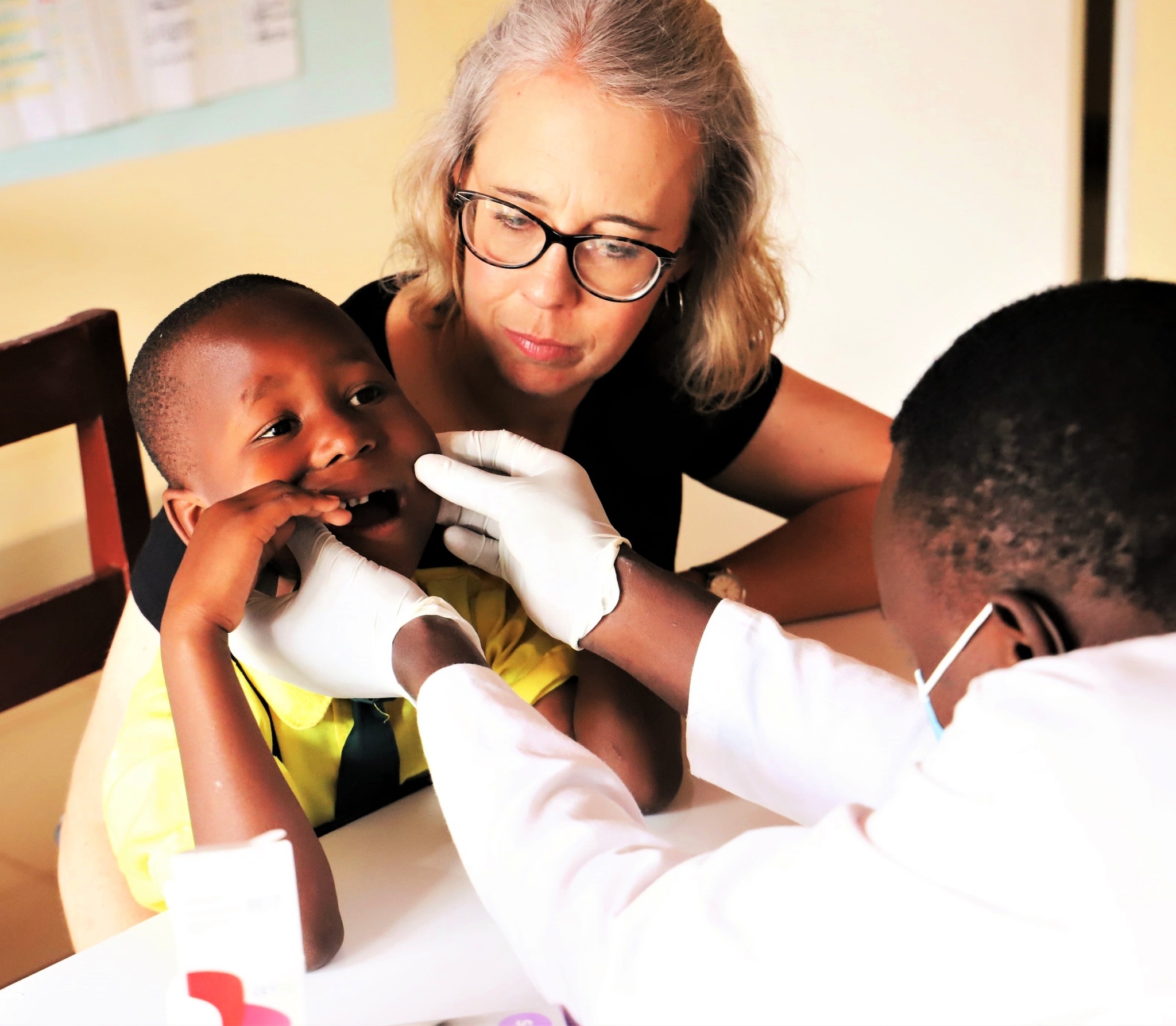 ACU nursing instructor Rebekah Mullins comforts one of the patients receiving a dental examination at Rwanda Children.
