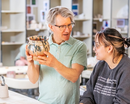 ACU Art student listens as a professor critiques her pottery