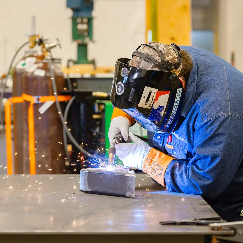 Engineering student is welding as sparks fly.
