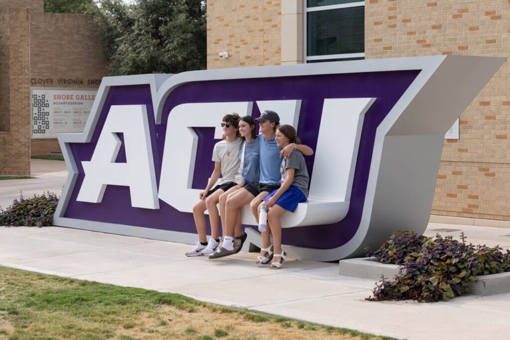 Students sitting on the ACU lettering on campus