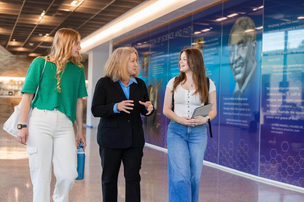 A teacher walking and talking with two students.