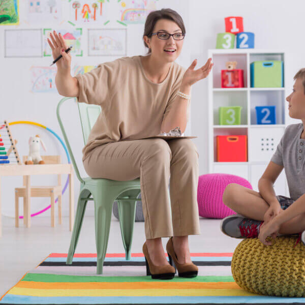 A women explaining a concept to a child on a bean bag chair within a classroom