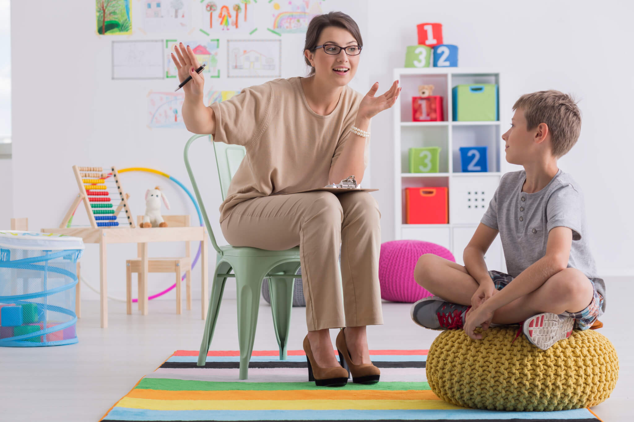 A women explaining a concept to a child on a bean bag chair within a classroom