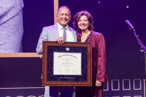 Dr. Phil Schubert and Amy Grant pose holding a framed honorary doctorate.