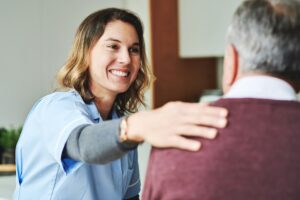 Woman in scrubs smiling with elderly man