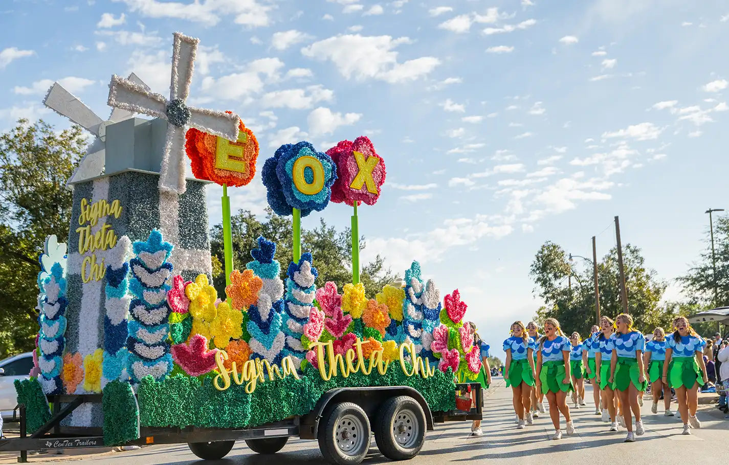Sigma Theta Chi sorority members march behind their float during the Homecoming parade.