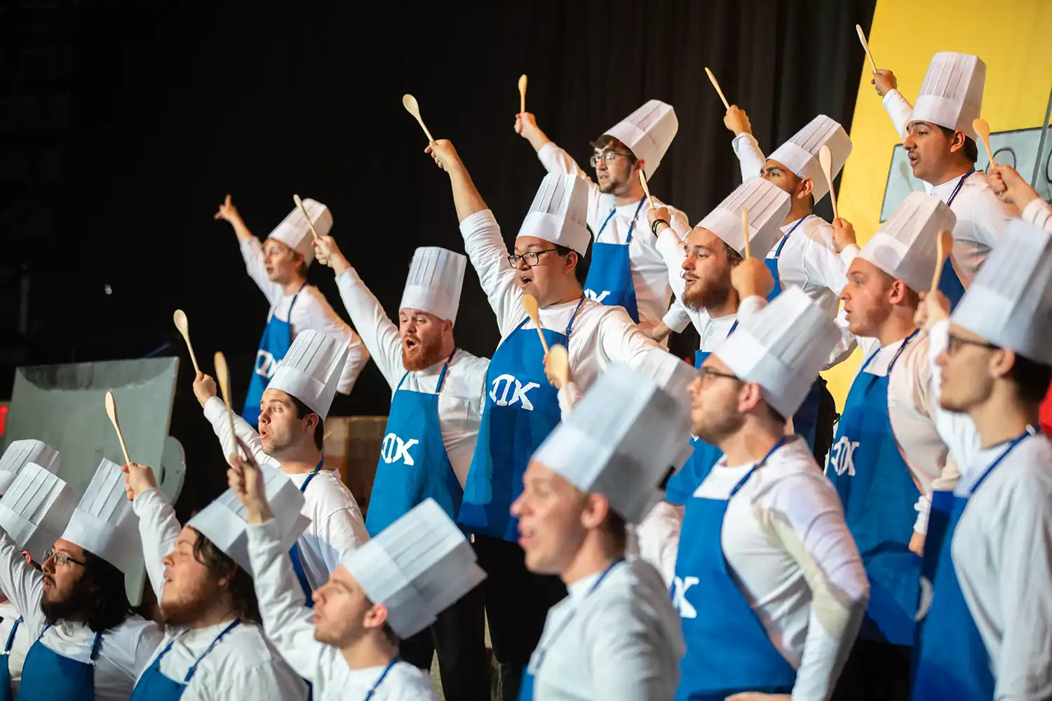 Pi Kappa members perform at Sing Song in baker costumes.