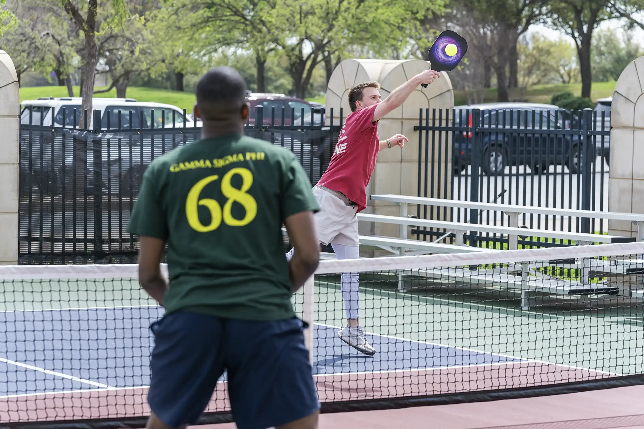 Two students play pickleball on the rec center's outdoor courts.