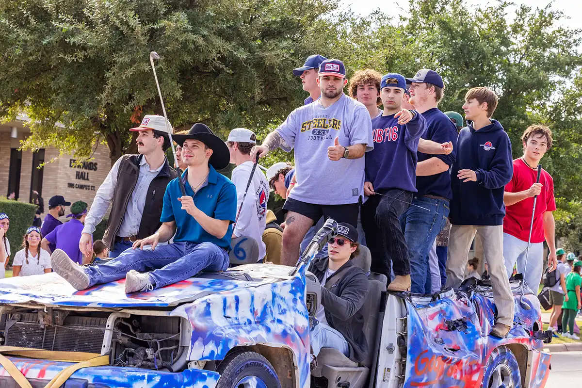 Sub T-16 members ride their float, an extremely beat-up car, during a Homecoming parade.