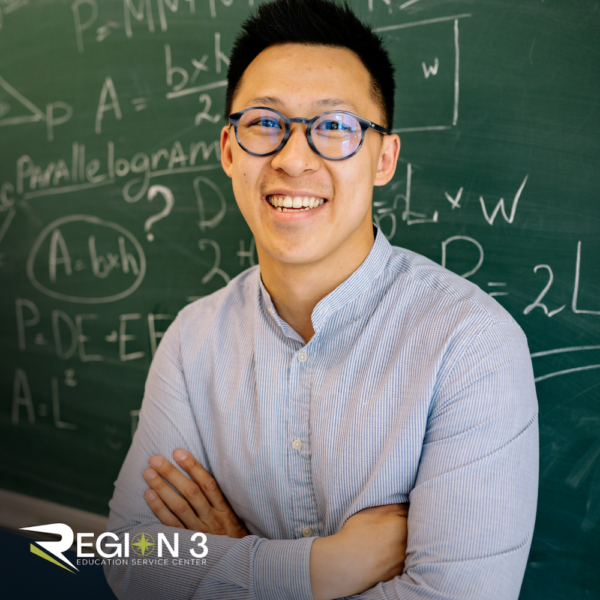 Teacher smiling in front of chalk board
