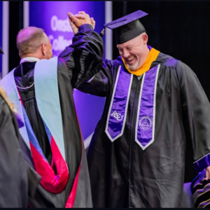 Bucky high-fiving faculty during graduation ceremony. 