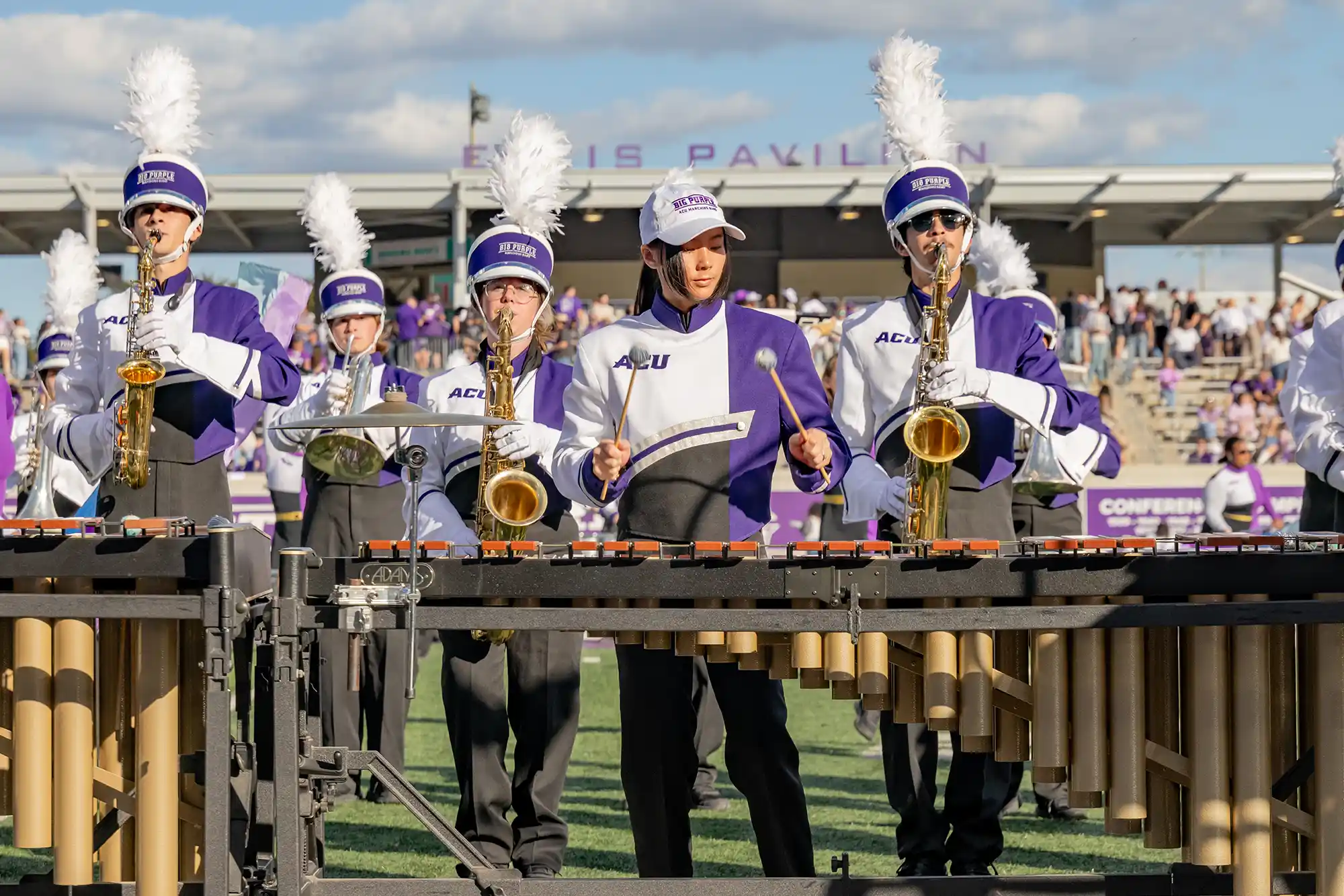 A marimba player with saxophones behind during a halftime show of the Big Purple Marching Band.