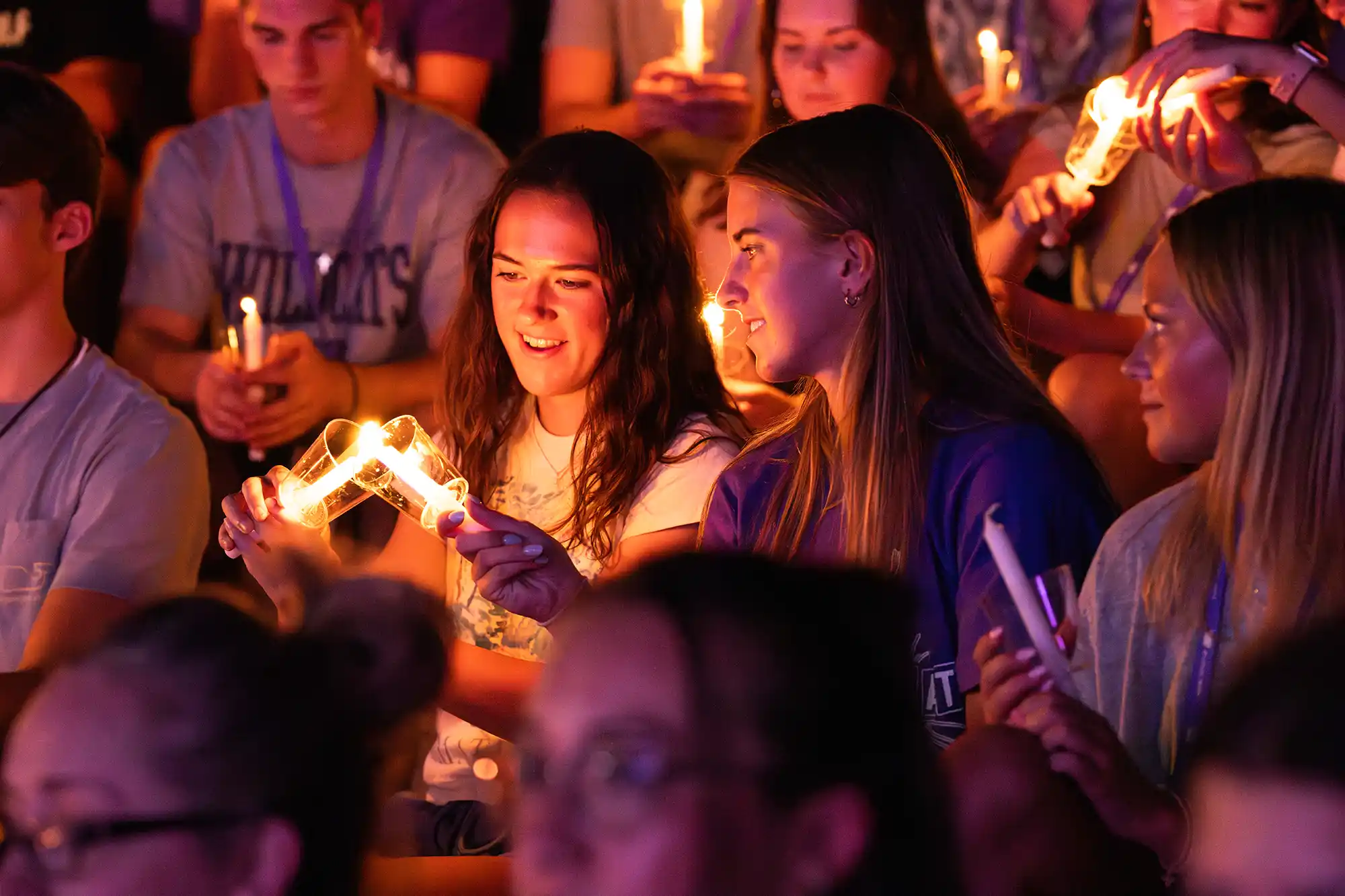 Students light each others' candles during Candlelight Devo during Wildcat Week.