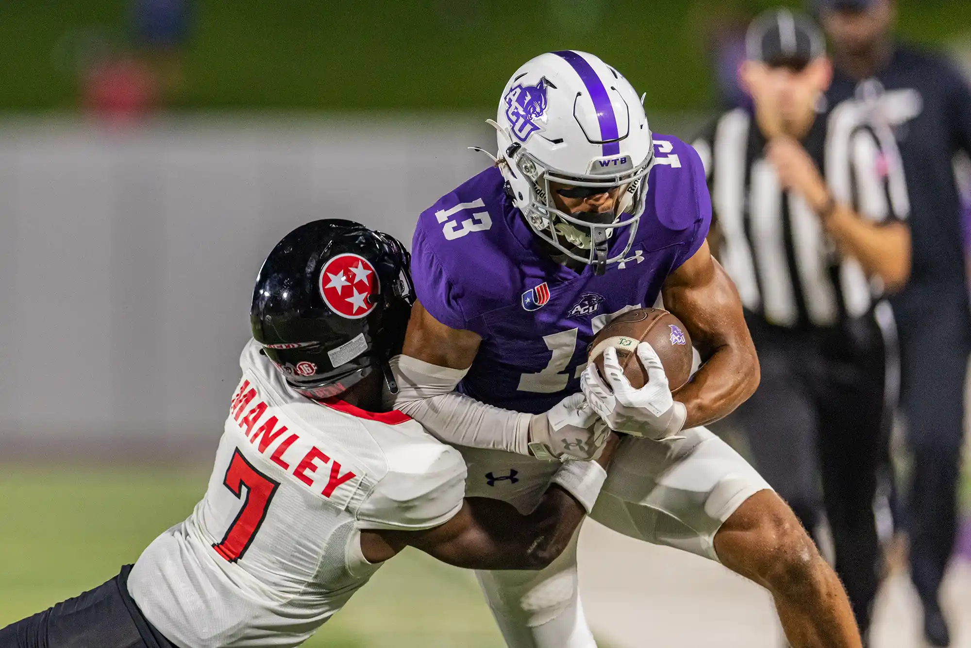 ACU football player being tackled while rushing with the ball.