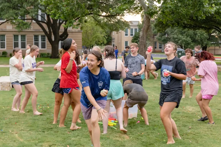 Rising Scholar students having a water balloon fight on the quad.
