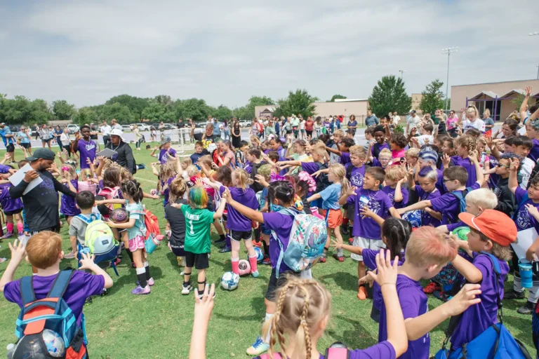 Dozens of kids dressed in their purple shirts wait for soccer sport camp to begin.