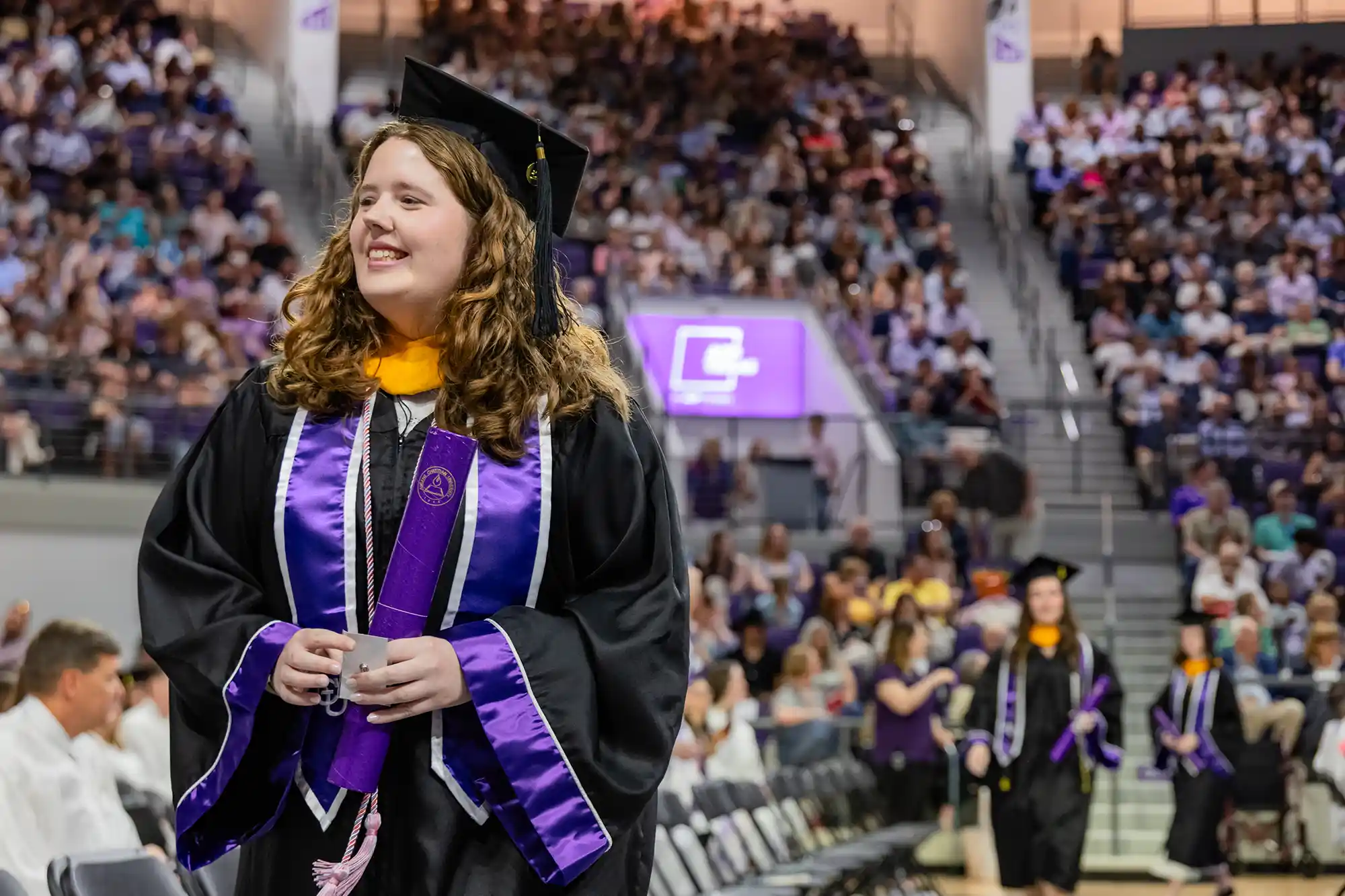 A new graduate walks back to their seat with a diploma during Commencement.