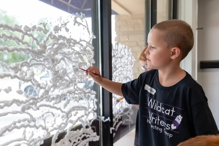 Kids at ACU's Writer Camp are writing with shaving cream on windows.